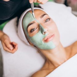 Cosmetologist applying mask on a face of client in a beauty salon